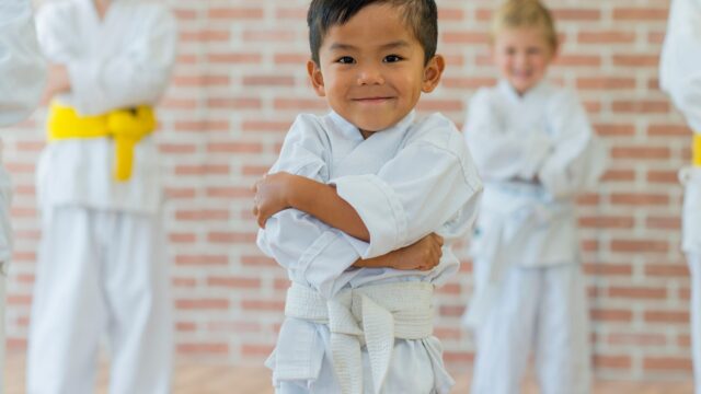 en liten pojke i judodräkt med armarna i kors